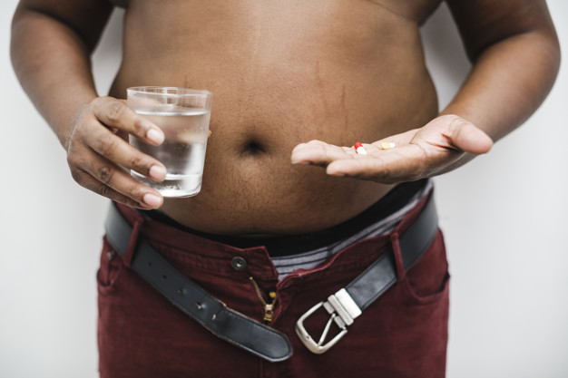 Overweight man taking a pill
